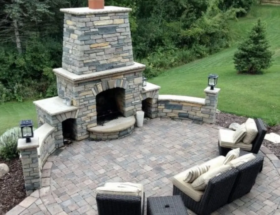 Outdoor stone fireplace and seating area on a paver patio
