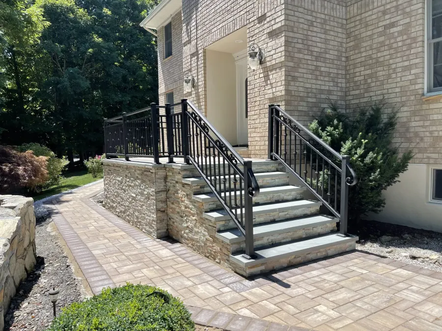 Stone front steps with black railings and a paver walkway