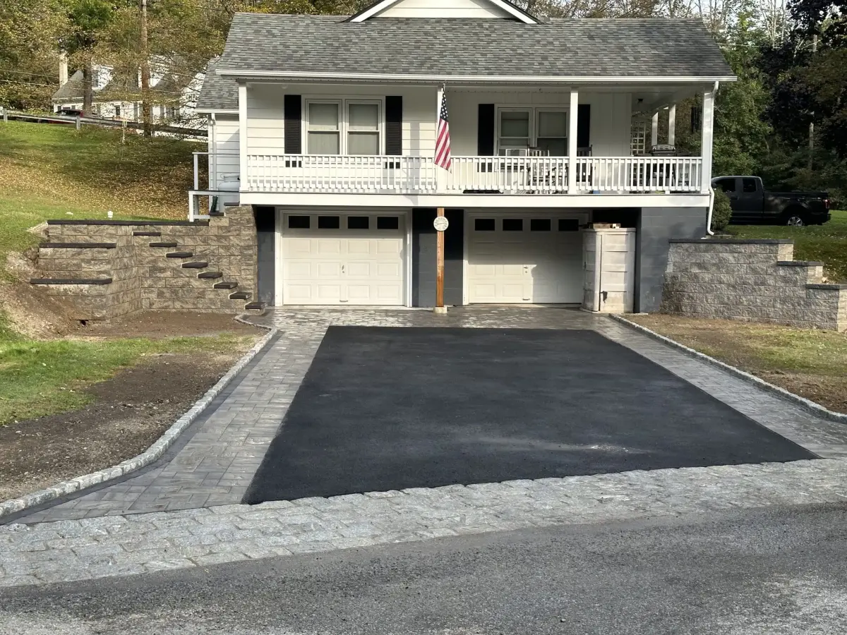 Asphalt driveway with a paver border leading to two garages