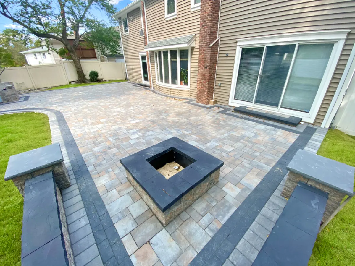 Square masonry fire pit centered in a paver patio