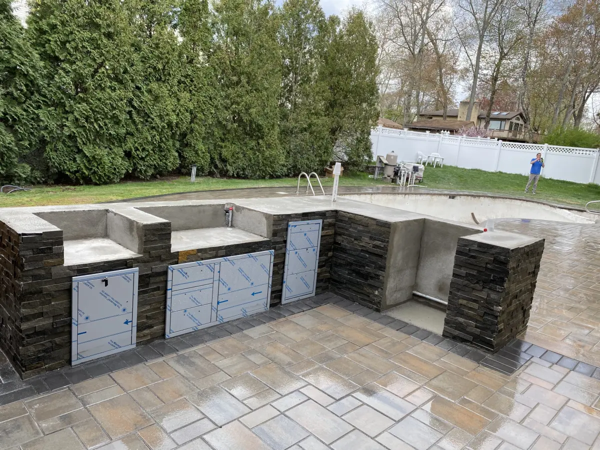 Outdoor kitchen island under construction beside a pool patio