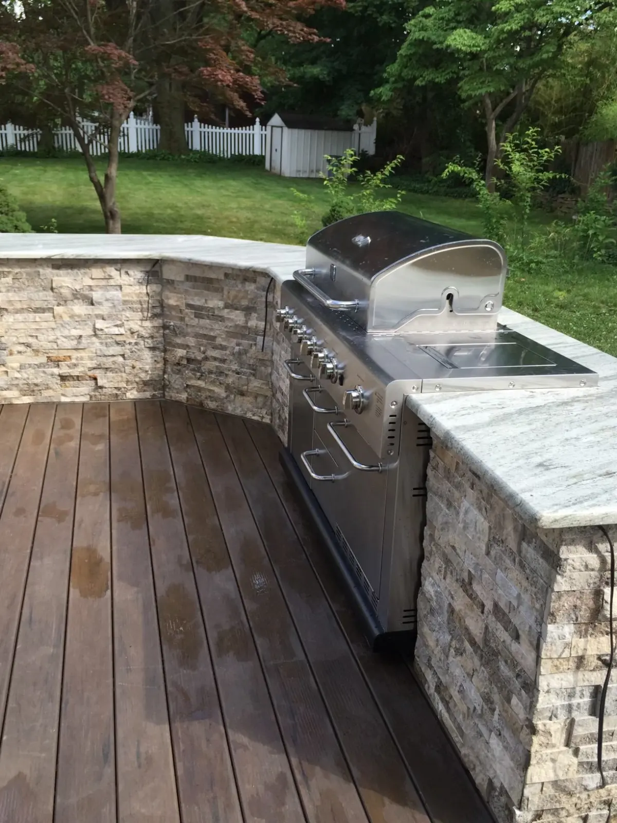 Built-in grill with a stone surround on a deck