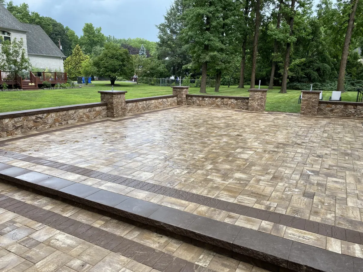 Large backyard paver patio with low stone walls