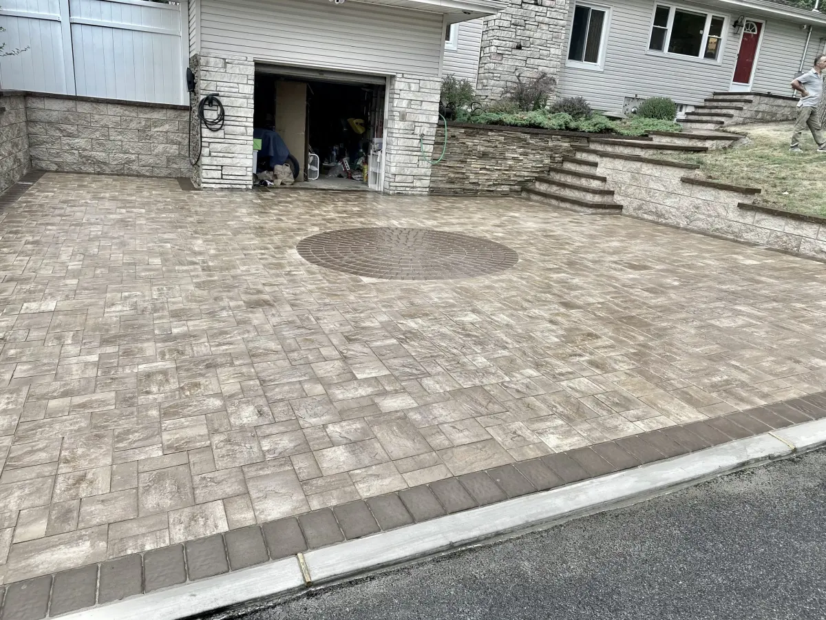 Paver courtyard beside a garage and stone retaining walls