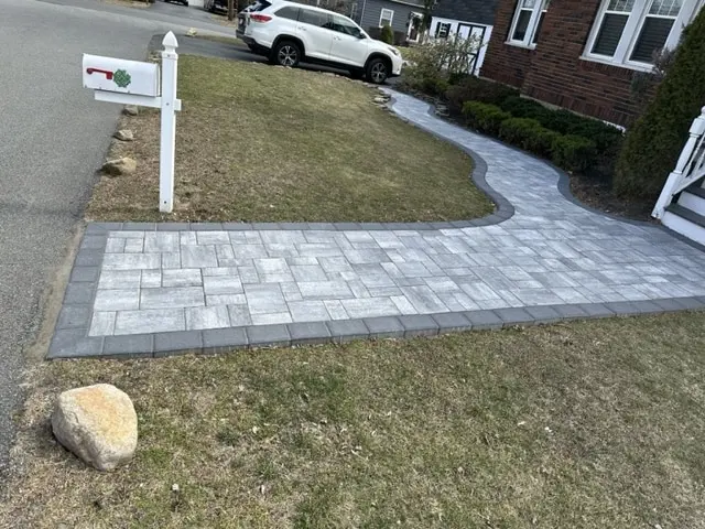 Wide paver walkway curving from the street toward a house