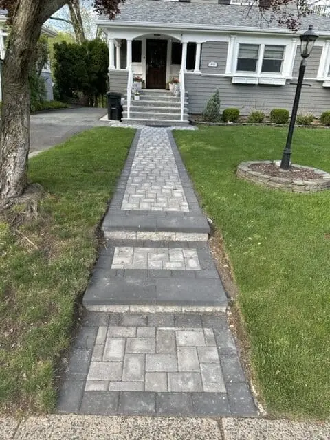 Straight paver walkway with two low steps leading to a front entrance