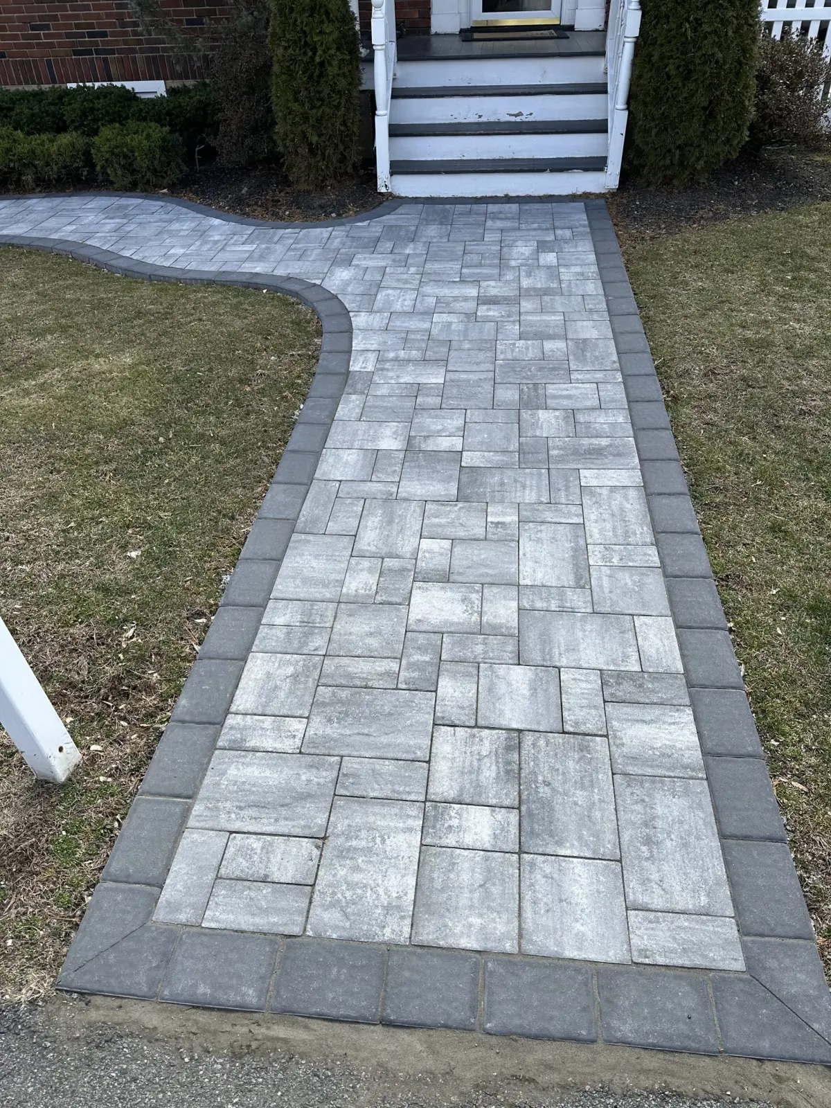 Gray paver walkway with a dark border at a front entrance