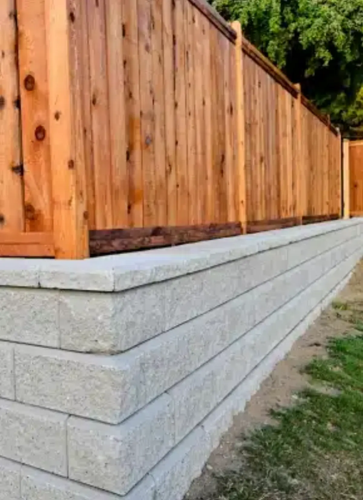Retaining wall supporting a wood fence along a property edge
