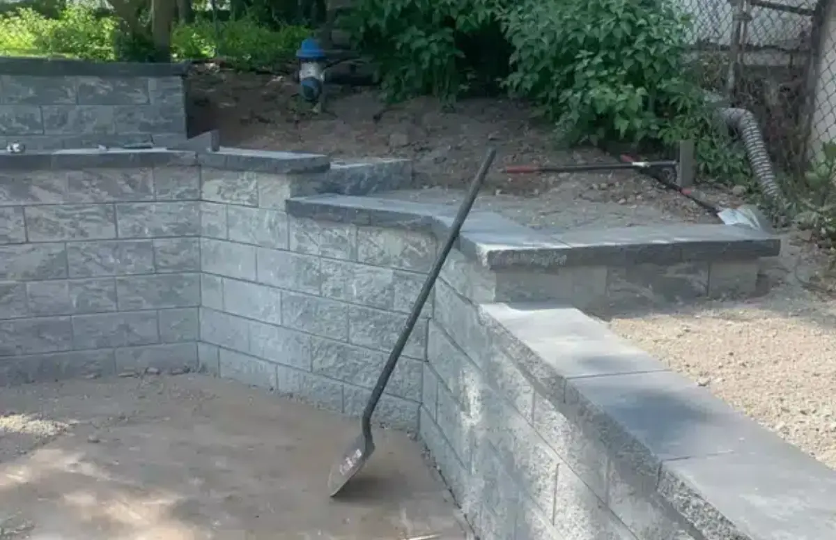 Block retaining wall with a capped edge and integrated steps